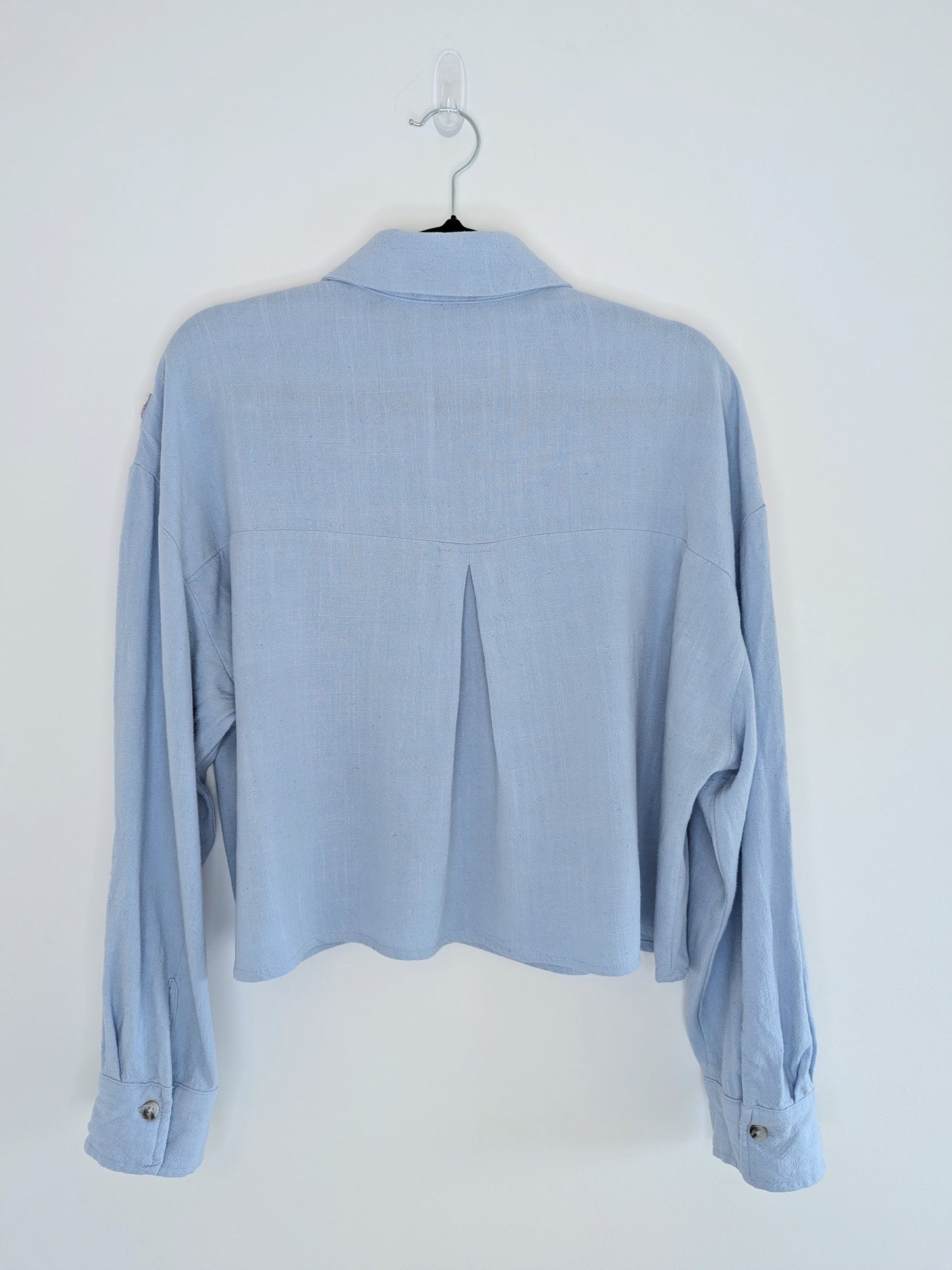 Light blue button-up shirt on a hanger against a white background