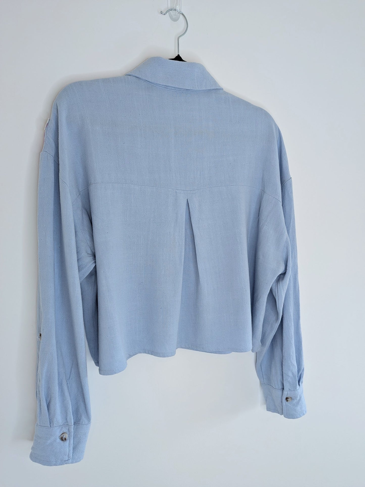 Light blue button-up shirt on a hanger against a white background