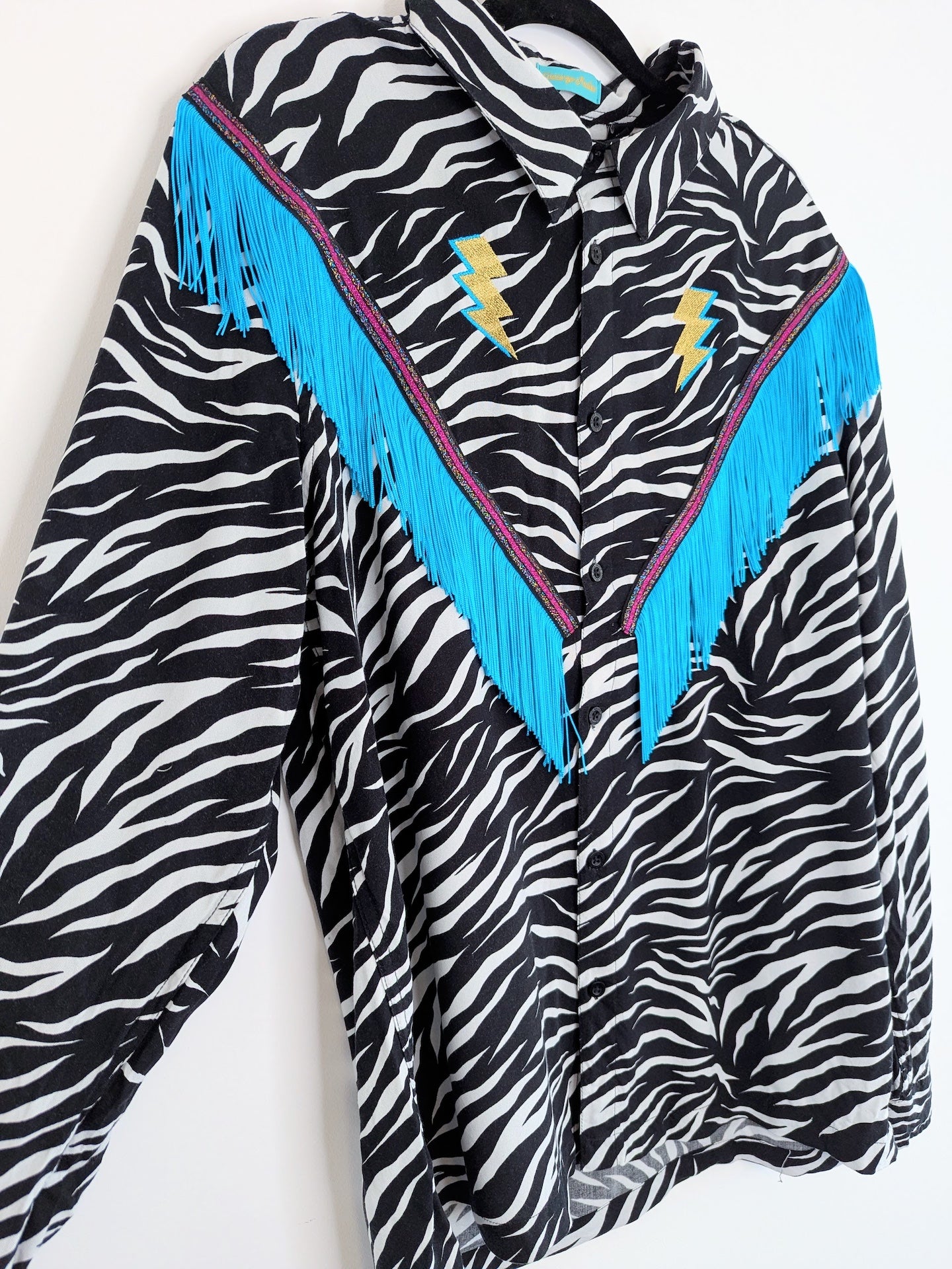 rodeo style western fringe shirt with embroidered  gold lighting bolts and turquoise tassel trim 