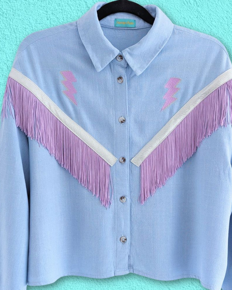 sky blue western shirt with lilac fringe trim and embroidery lightning bolts between the shoulder and chest on each side.