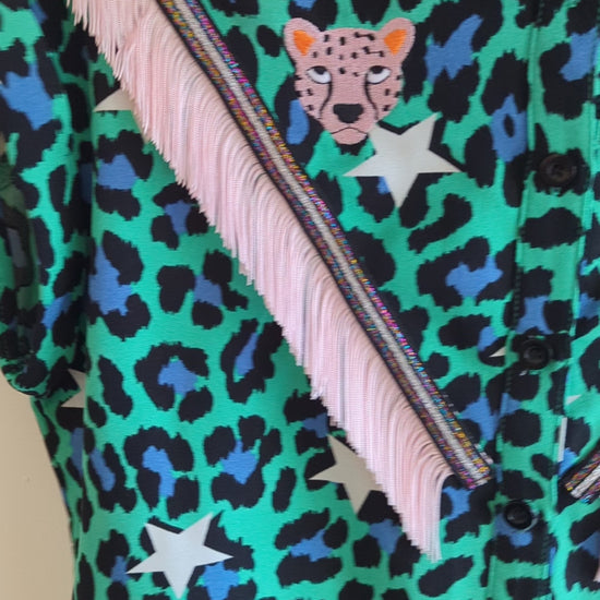 video of a green shirt with leopard print and star patterns. It has embroidery pink leopards and western style pale pink fringe trim added.