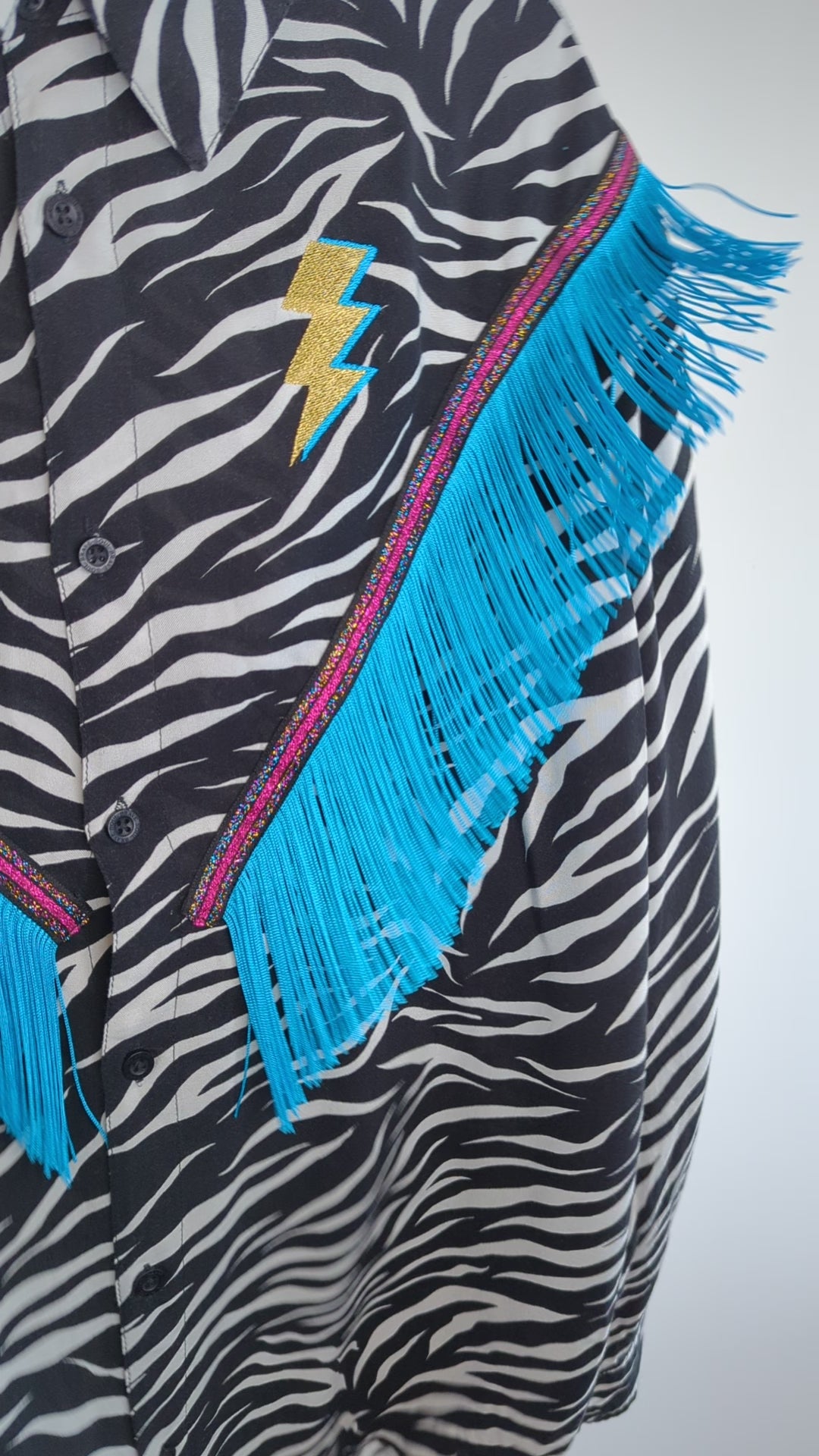 western rodeo style fringe shirt being shaken to show showing the movement of the tassel fringe