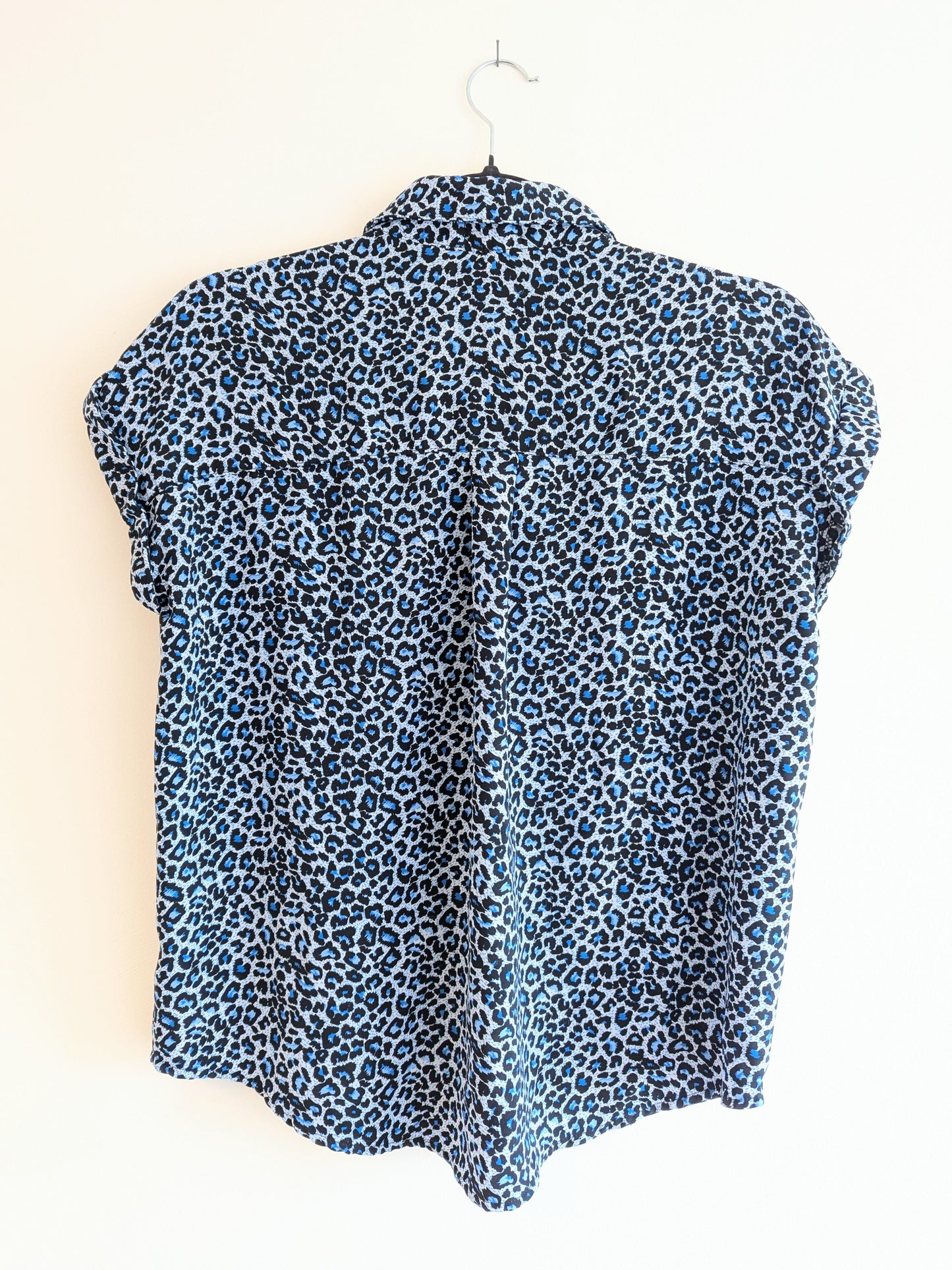 Blue leopard print sleeveless top on a hanger against a white background