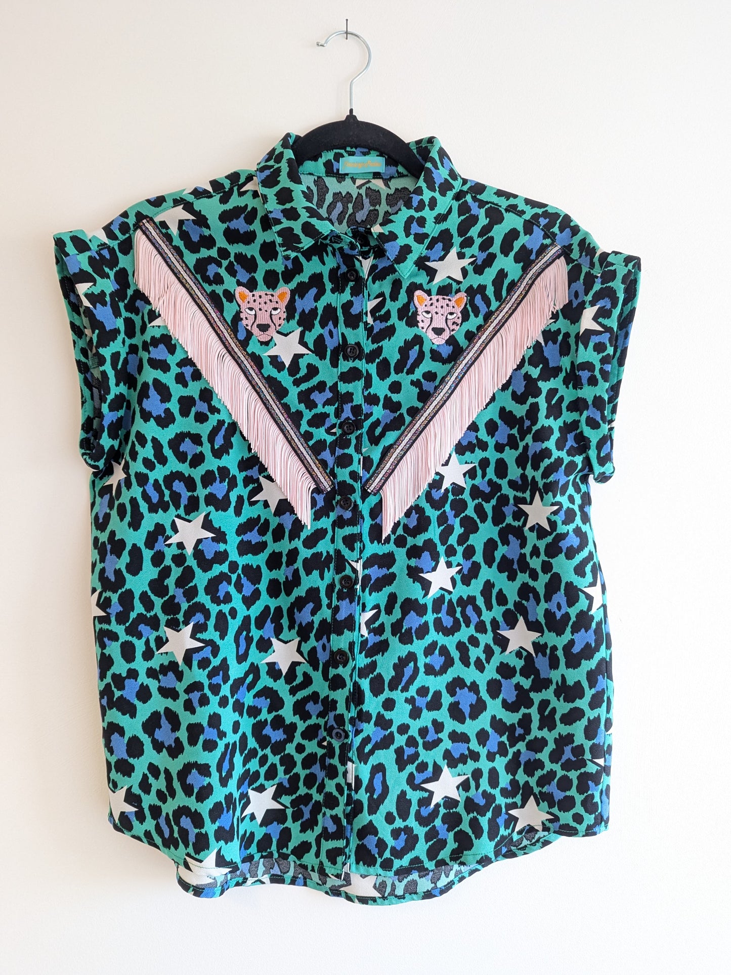 green shirt with leopard print and star patterns. It has embroidery pink leopards and western style pale pink fringe trim added.