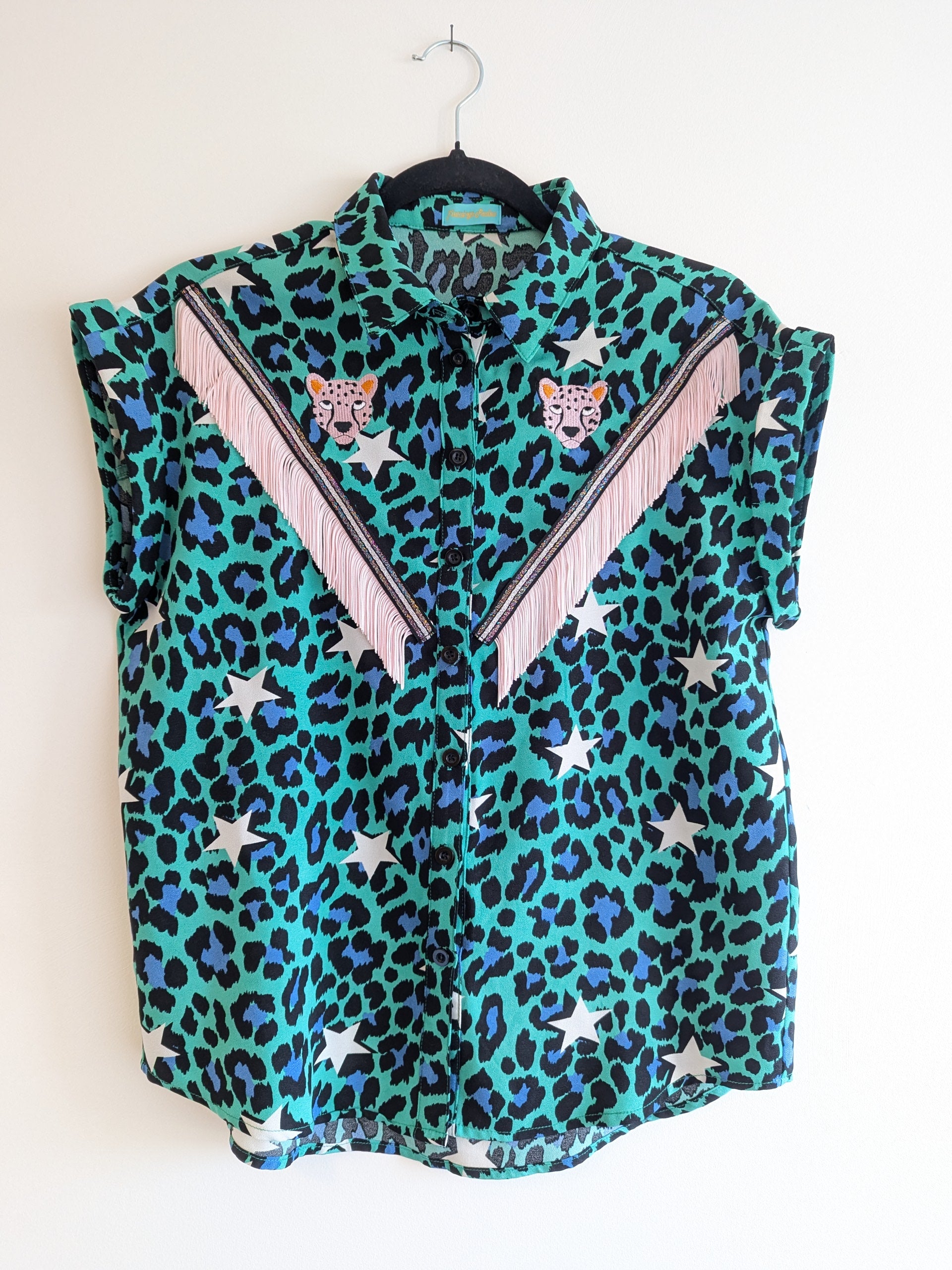 green shirt with leopard print and star patterns. It has embroidery pink leopards and western style pale pink fringe trim added.